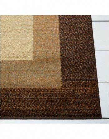 A brown and tan rug is sitting on a white floor.