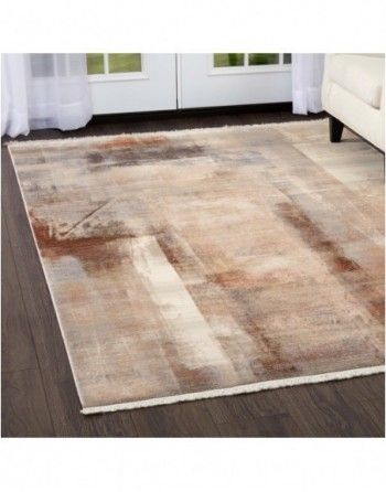 A rug is sitting on a wooden floor in a living room next to a couch.