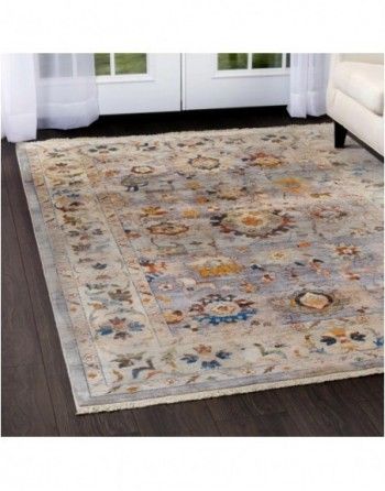 A rug is sitting on a wooden floor in a living room next to a couch.