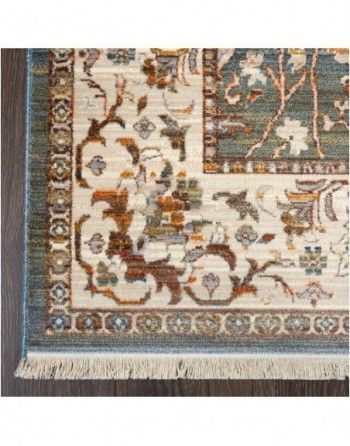 A rug with a floral pattern and fringe is on a wooden floor.