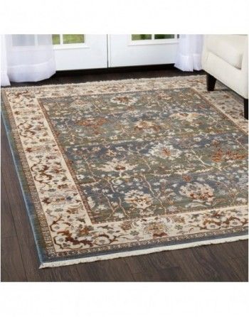 A rug is sitting on a wooden floor in a living room next to a couch.