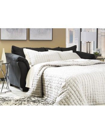 A black couch is turned into a bed in a living room.