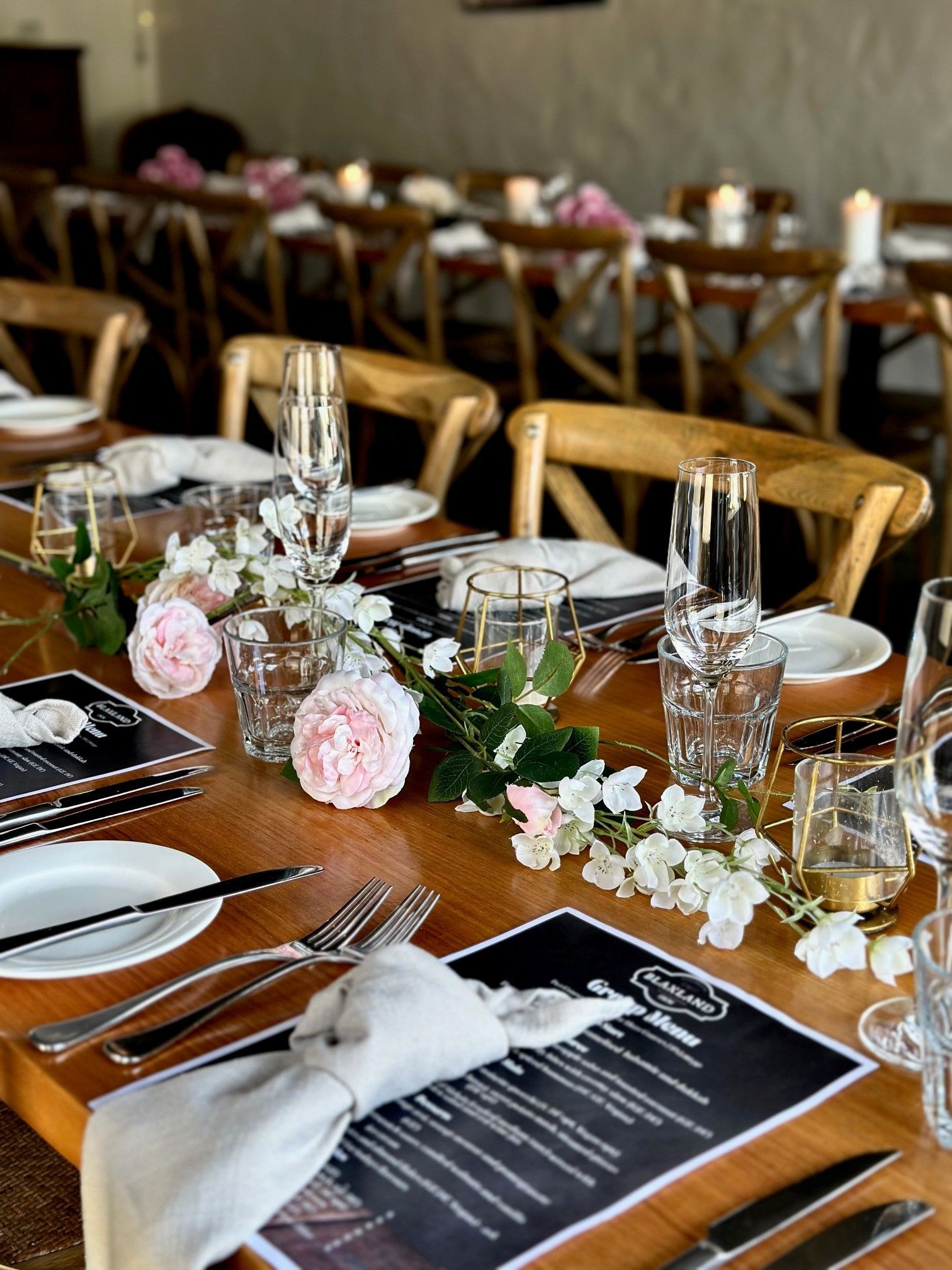 A long table with plates , glasses , and flowers on it.