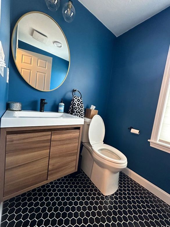 A bathroom with blue walls and a toilet and sink