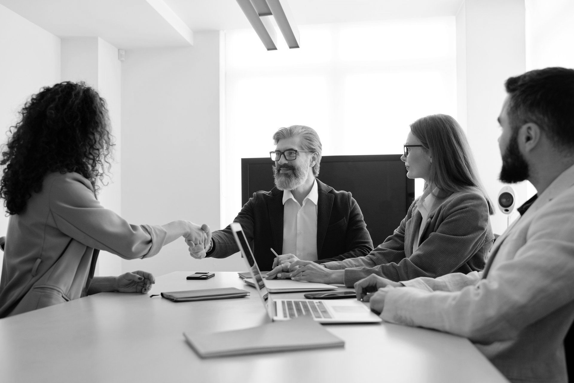 A group of people are sitting around a table shaking hands.