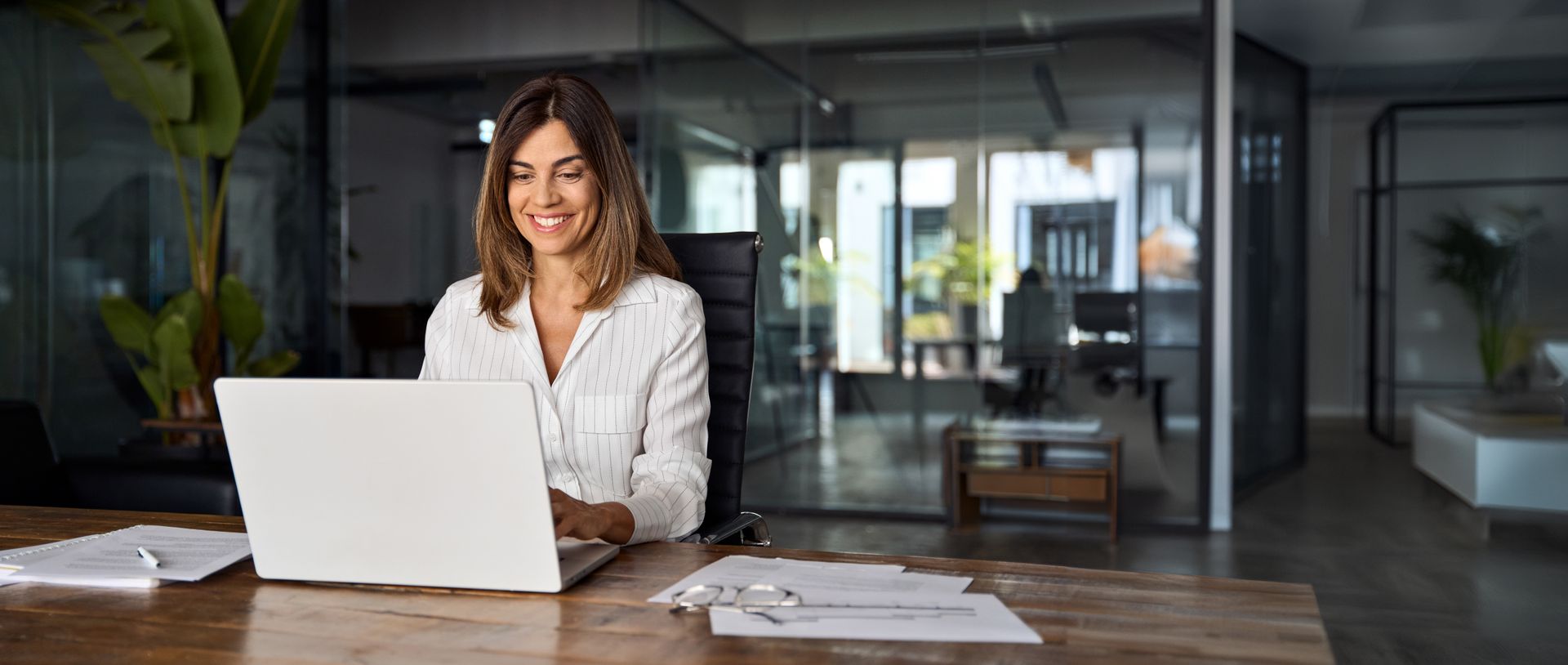 A woman is sitting at a desk using a laptop computer.