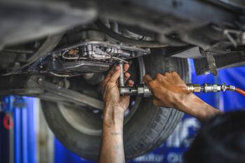 a man is working on the underside of a car in a garage