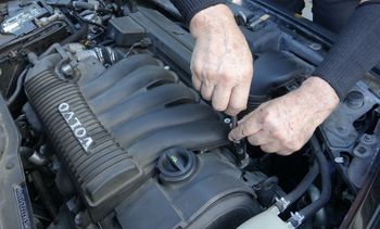 a man is working on the engine of a volvo car