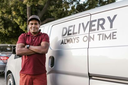 A delivery man is standing in front of a delivery van.