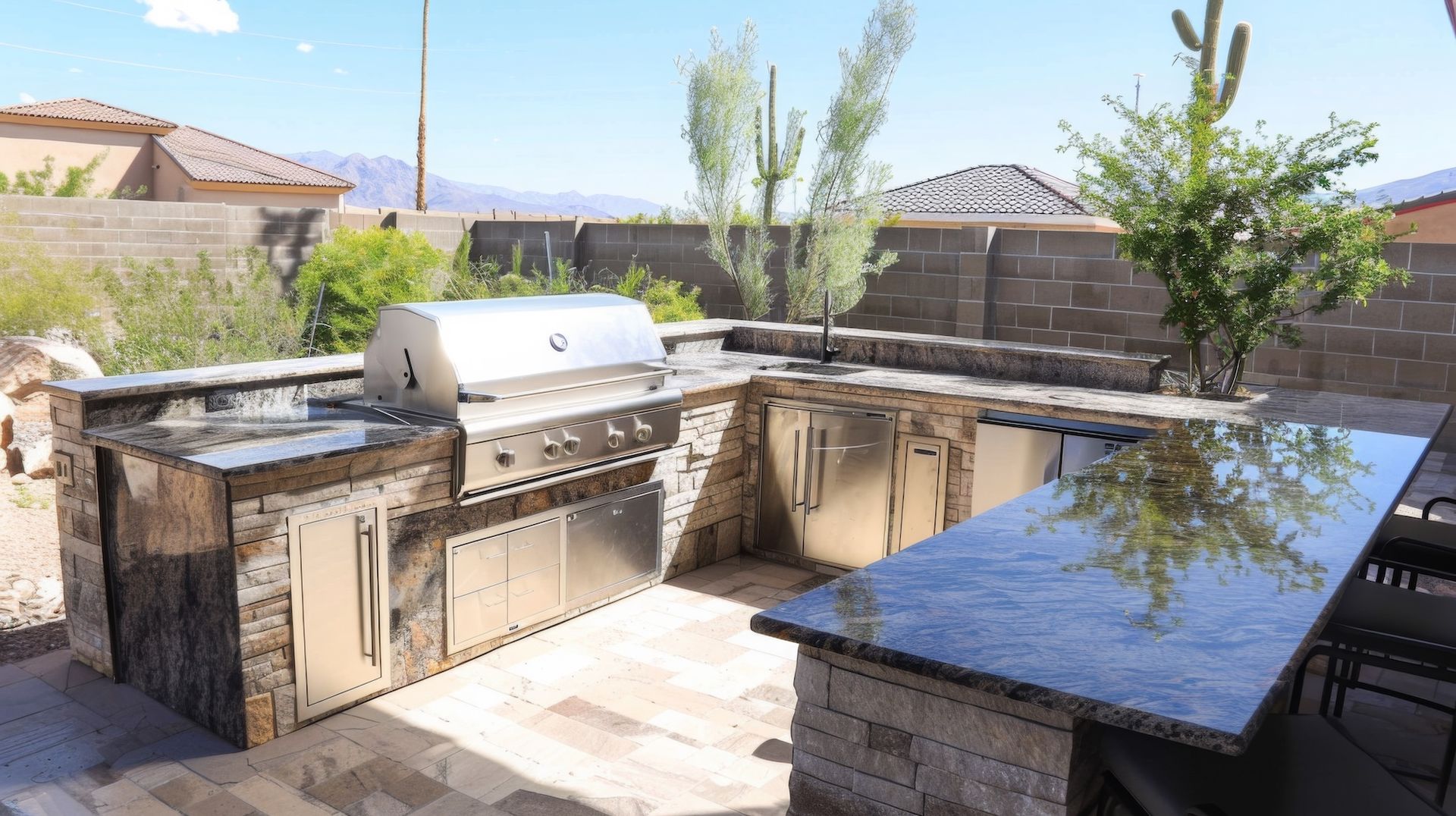 Outdoor kitchen with stainless steel grill, cabinets, and a granite countertop.