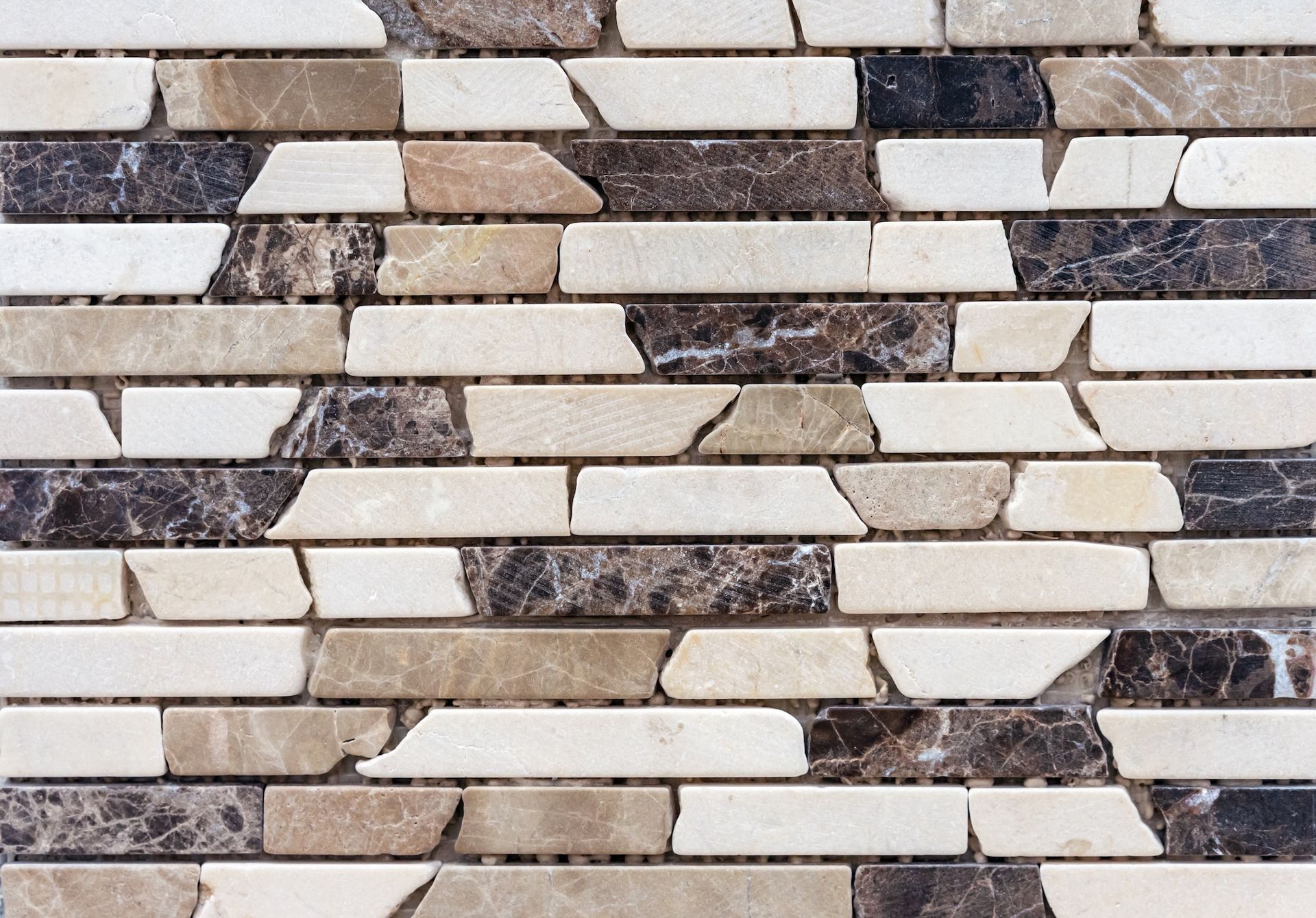 Mosaic tile pattern with beige, brown, and black irregular rectangular pieces.