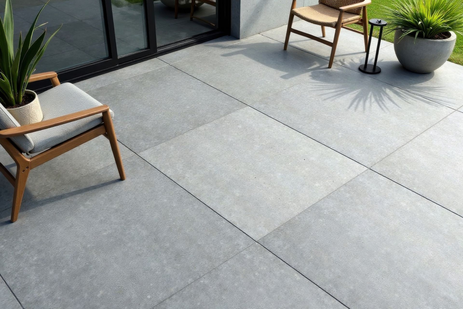 Gray tiled patio with two chairs, potted plants, and sliding glass door.