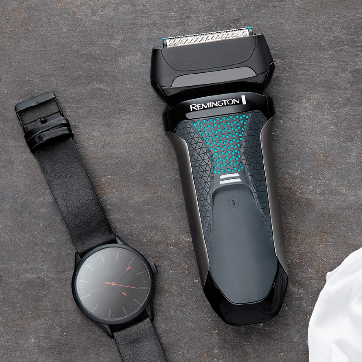 Electric shaver and black wristwatch on a gray surface.