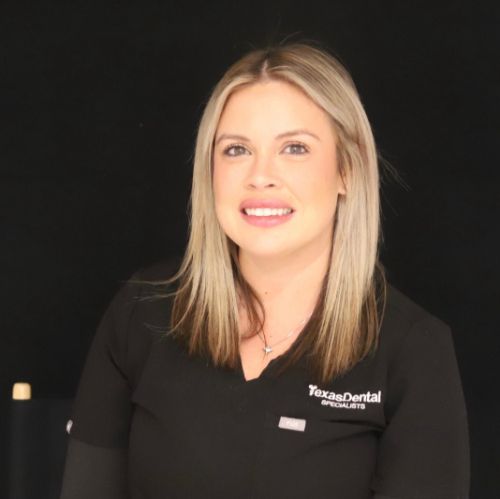 ashley in a black scrub top is smiling for the camera.