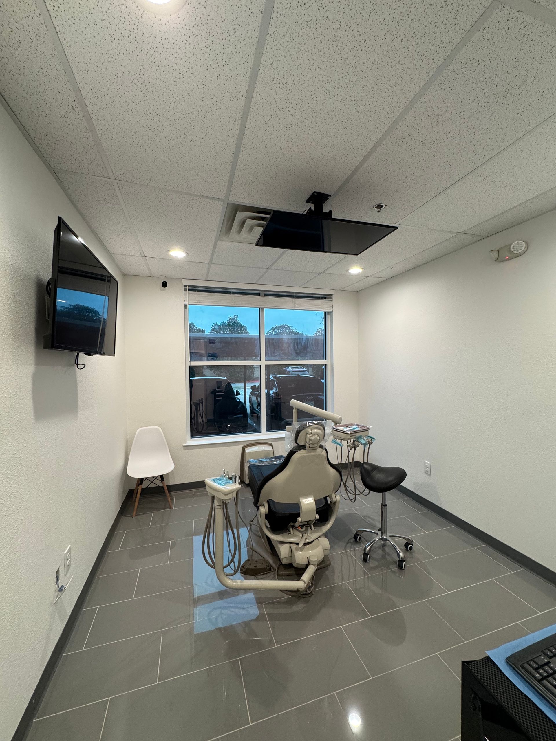 A dental office with a dental chair and a television on the wall.