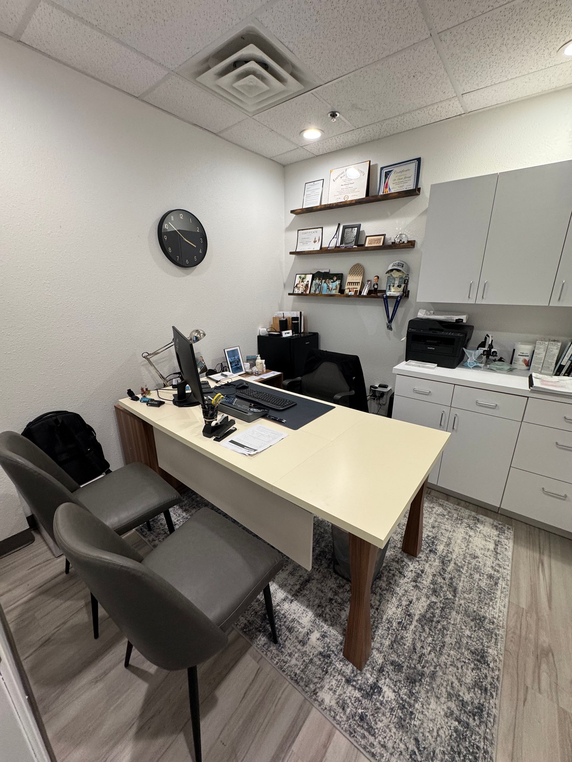 A small office with a desk and chairs and a clock on the wall.