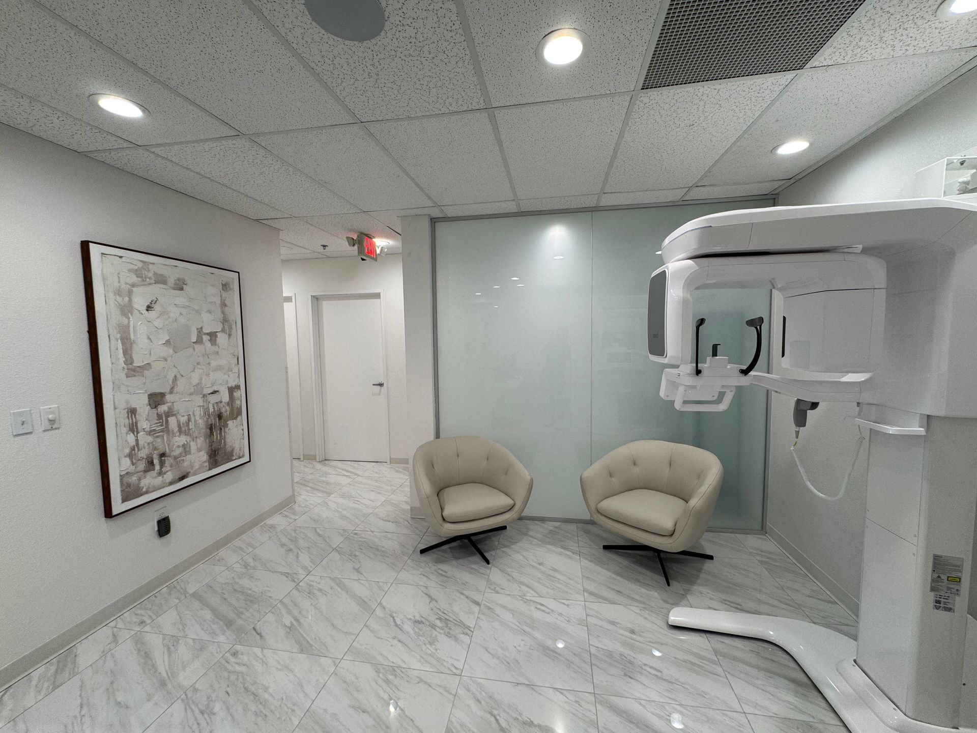 A dental office with two chairs and a x-ray machine.