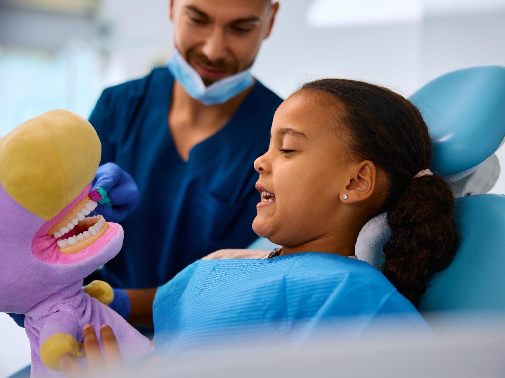 A little boy is sitting in a dental chair getting his teeth examined by a dentist.