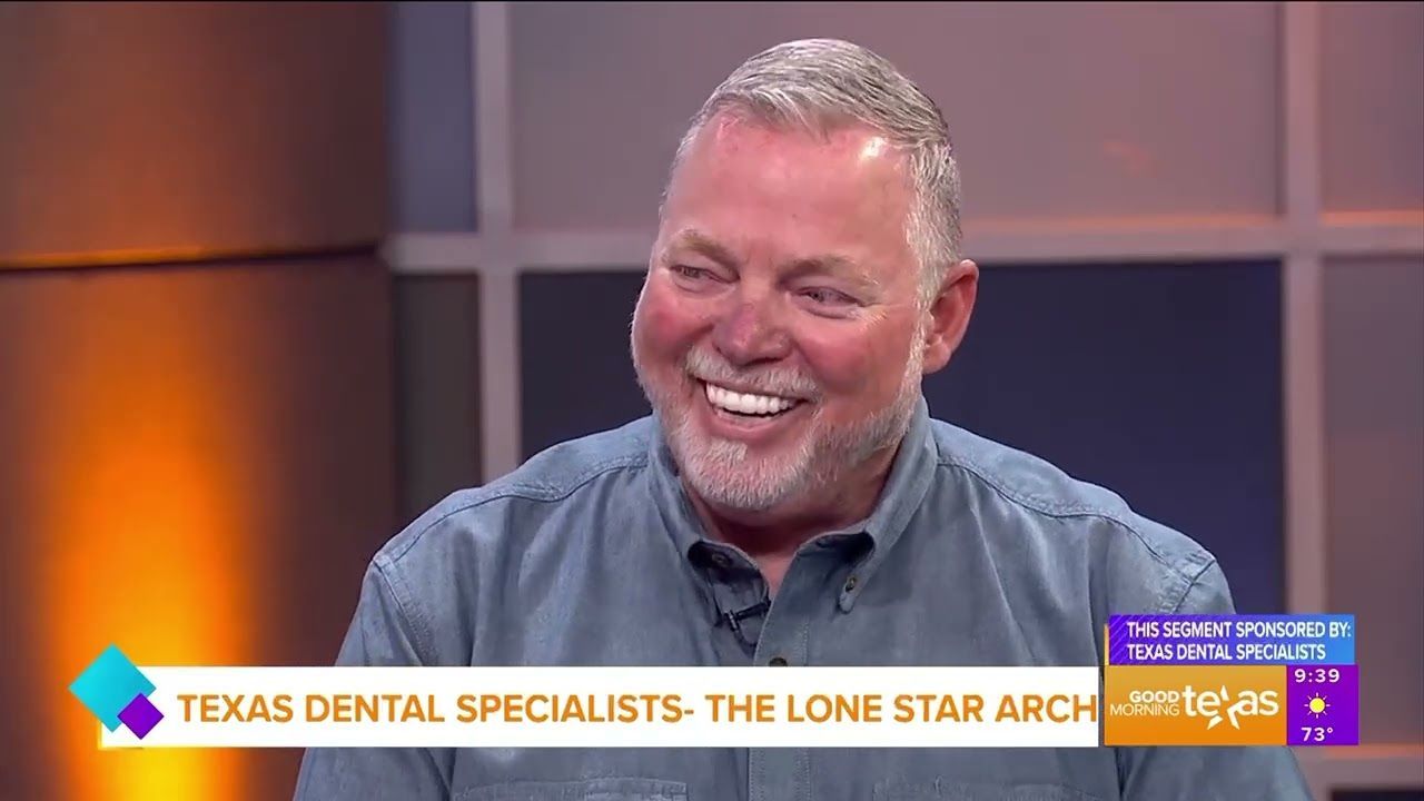 A man with a beard is smiling in front of a sign that says texas dental specialists