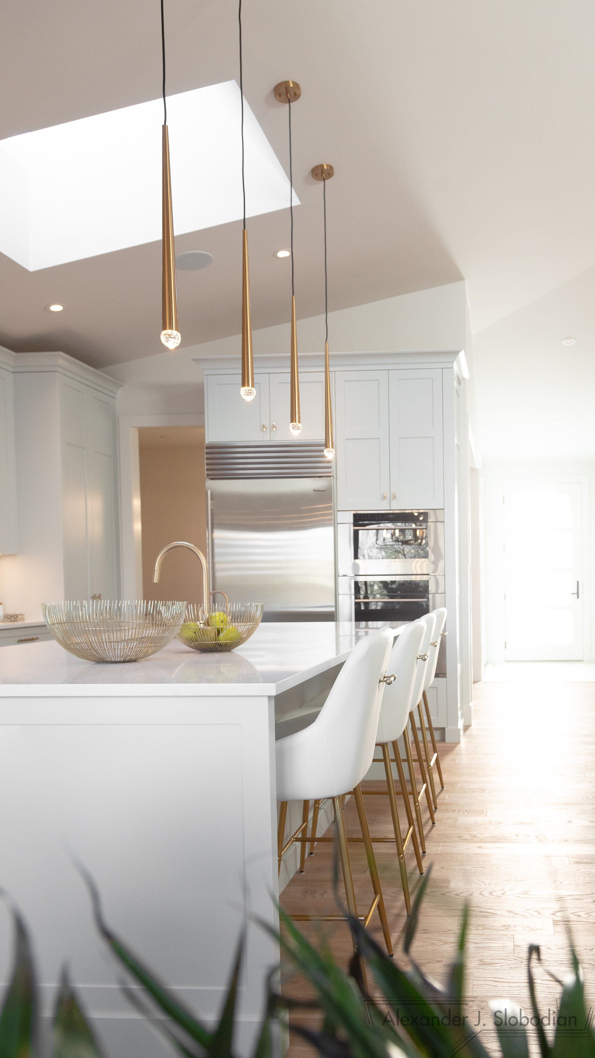 a kitchen with white cabinets , stainless steel appliances , and a large island .