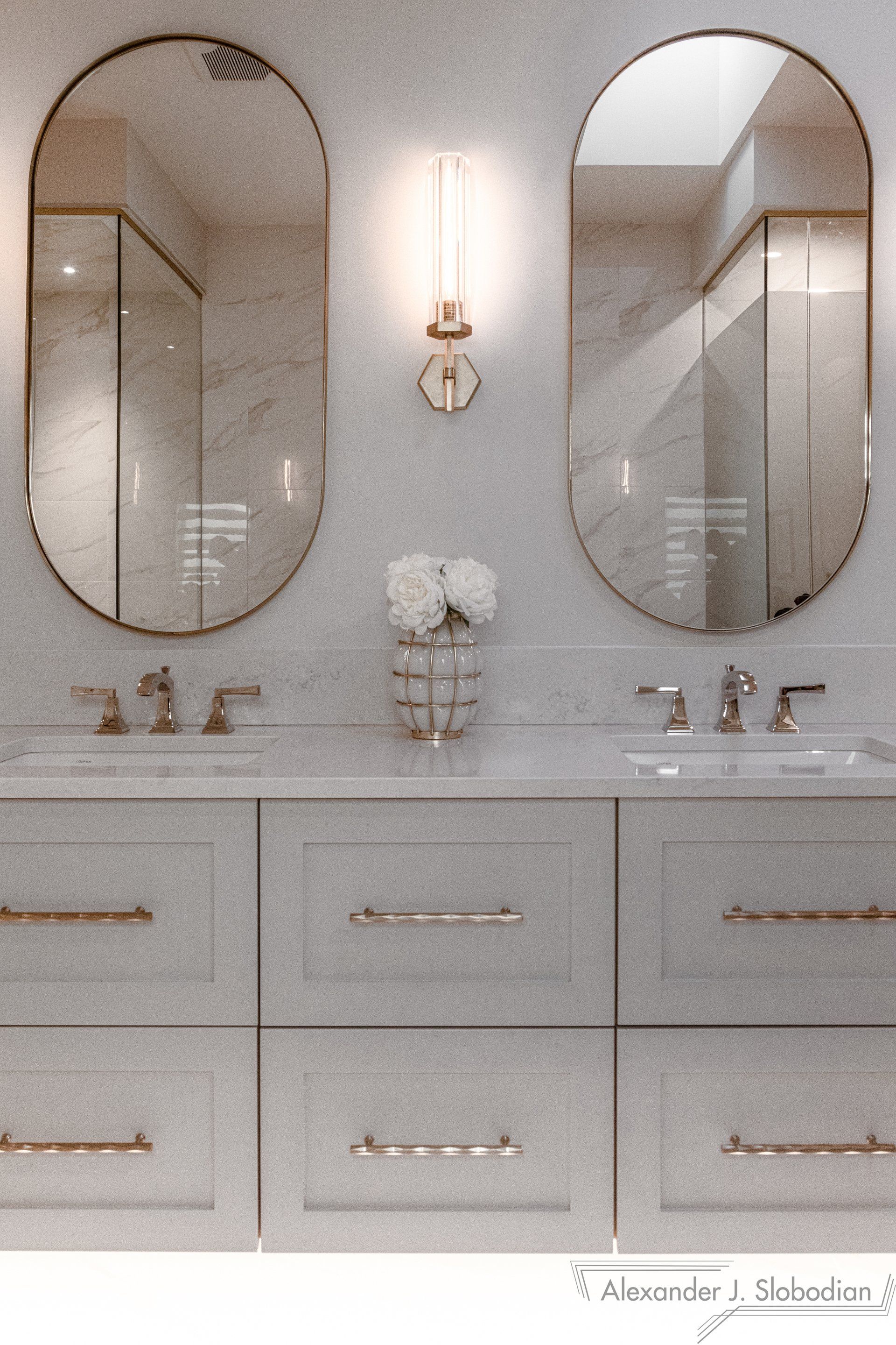 a bathroom with two oval mirrors and two sinks