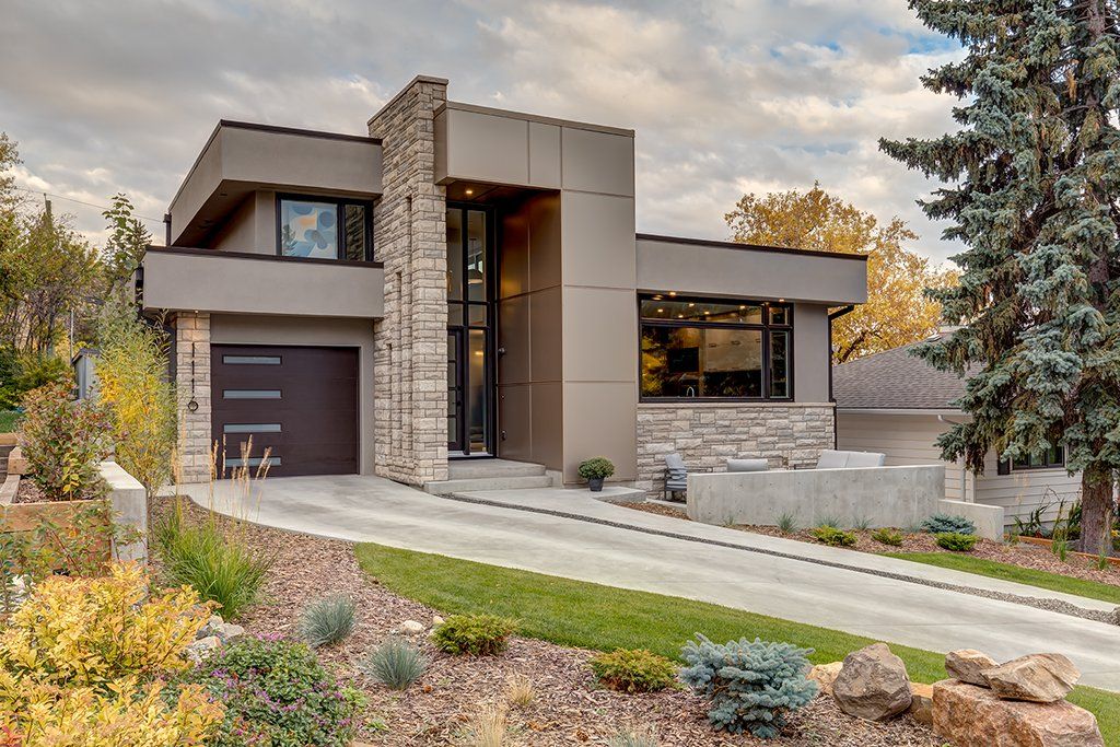 a large modern house with a large garage is sitting on top of a hill .