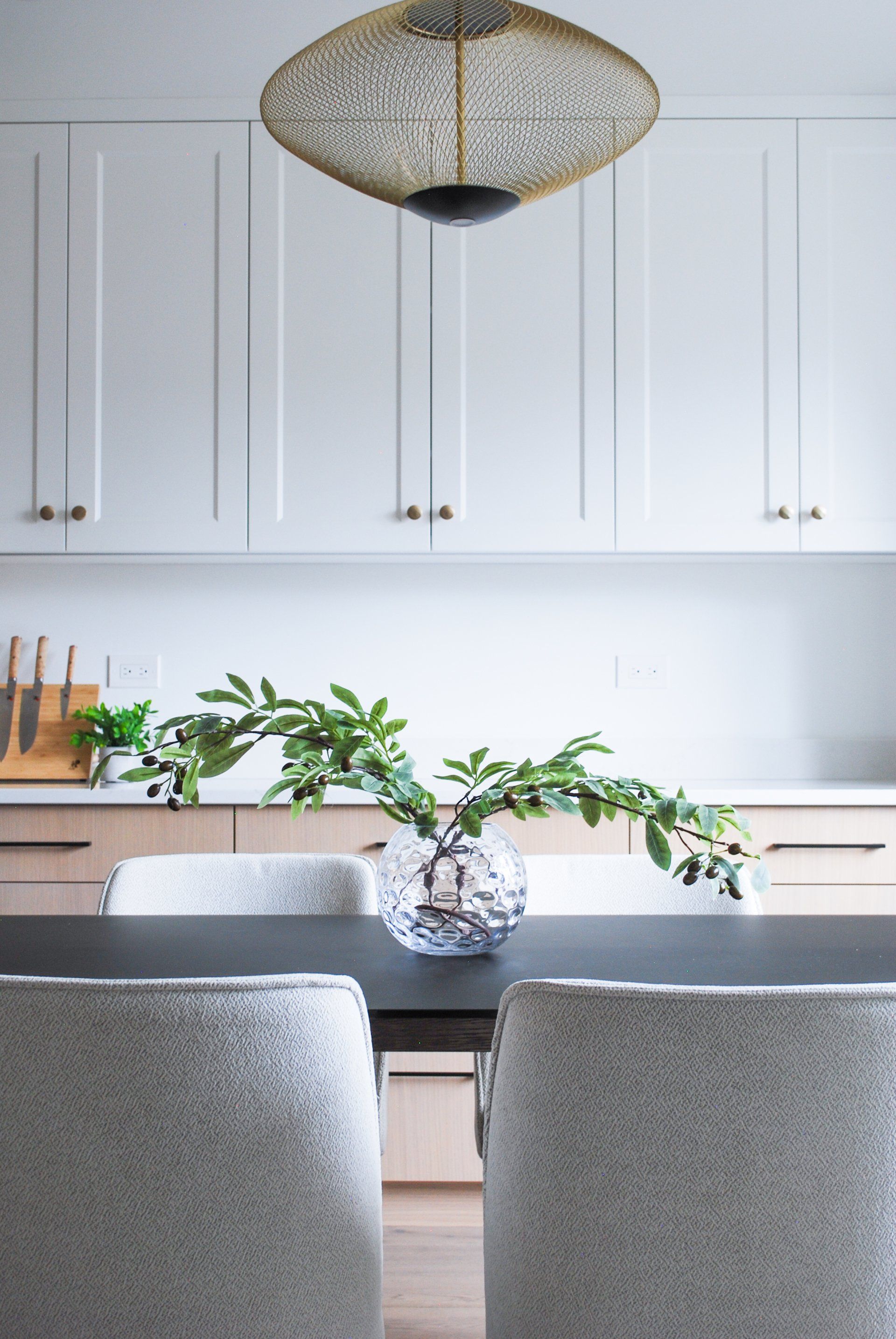 a dining room table with a vase of plants on it
