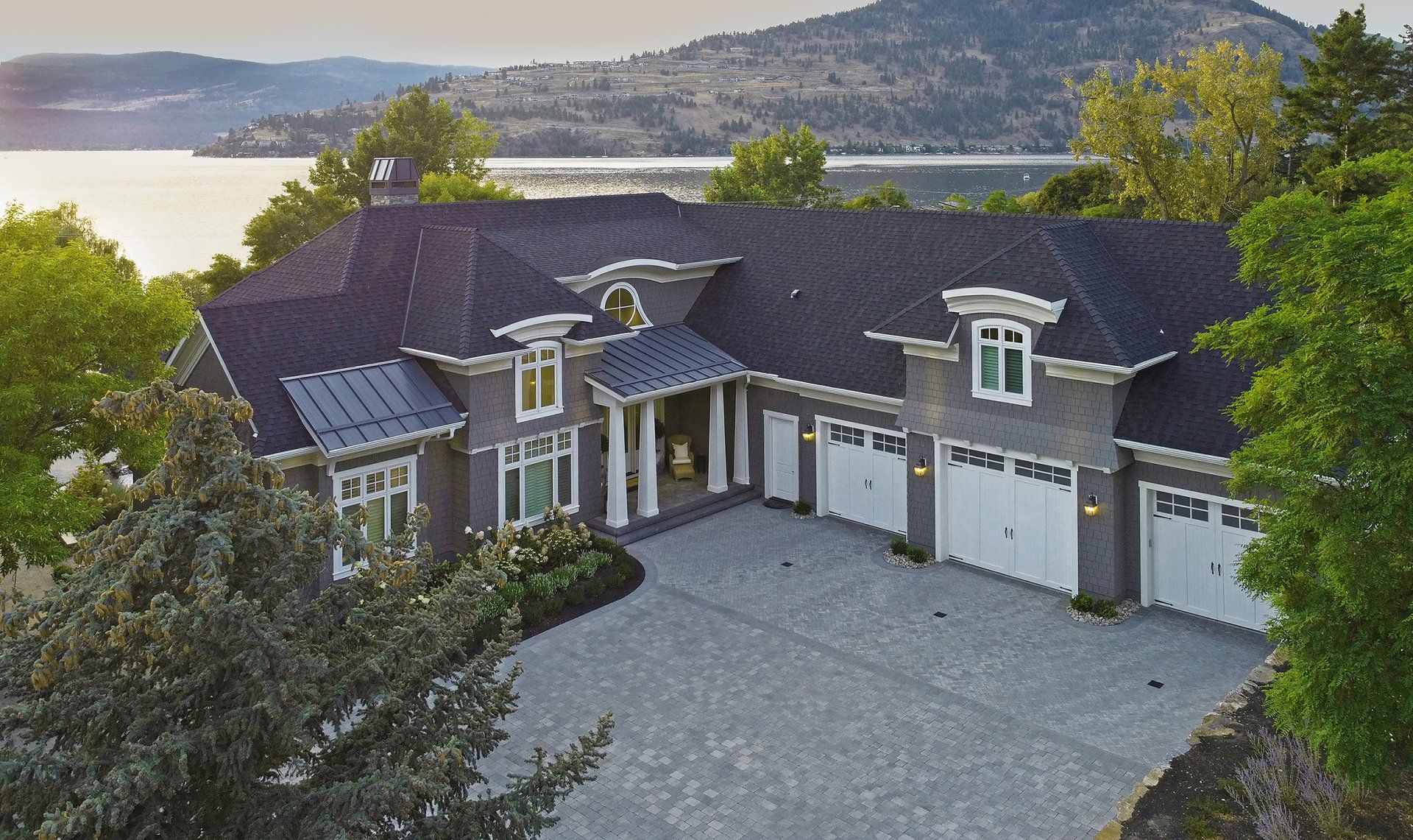 an aerial view of a large house with a lake in the background