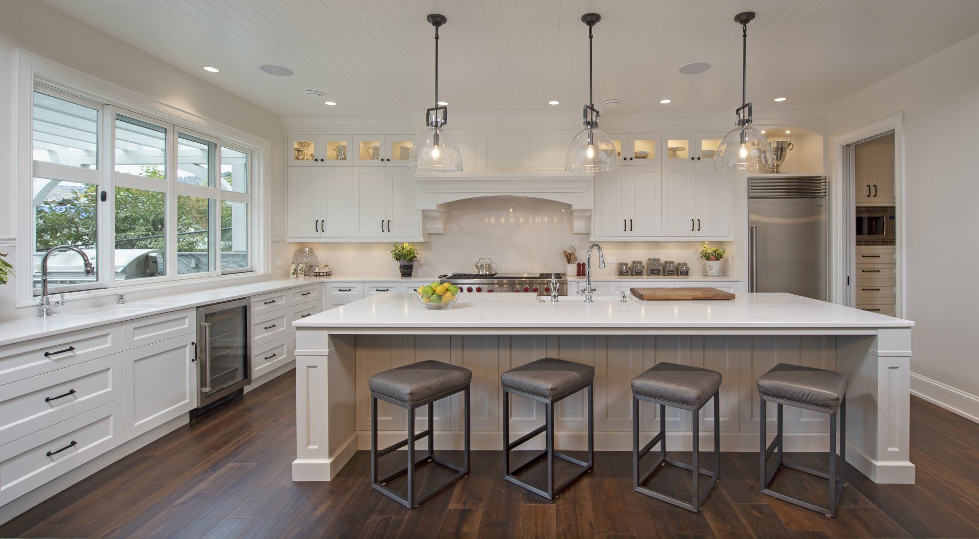 a kitchen with white cabinets and stools and a large island .