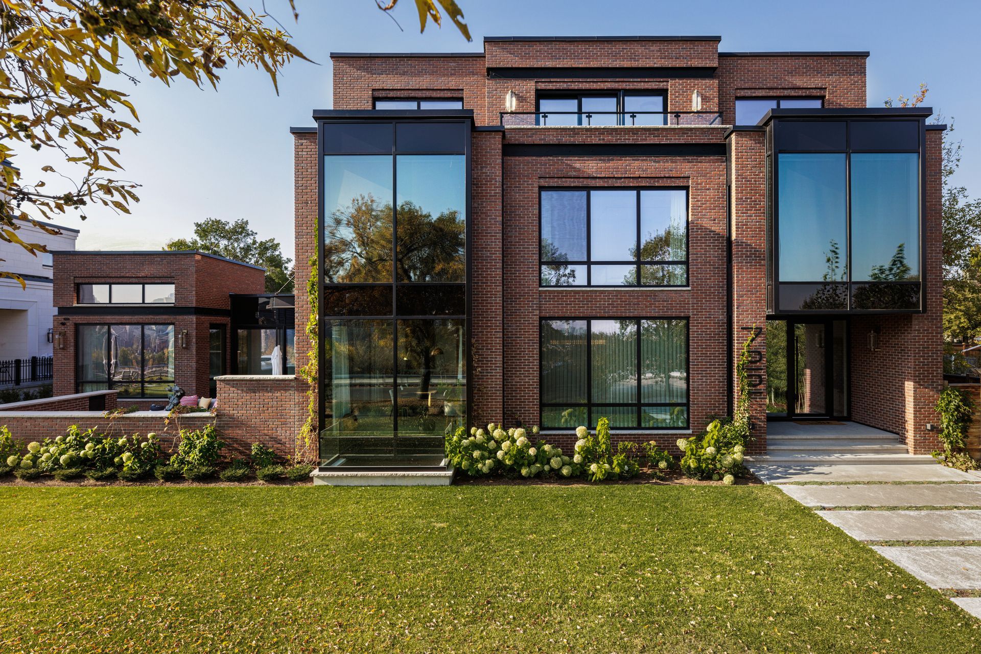 a large brick house with a lot of windows is sitting on top of a lush green lawn .