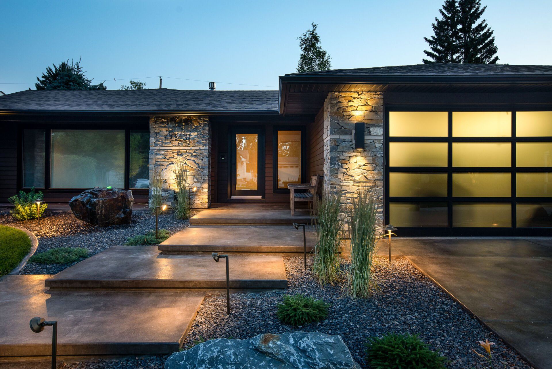 the front of a house with a glass garage door and steps leading up to it .