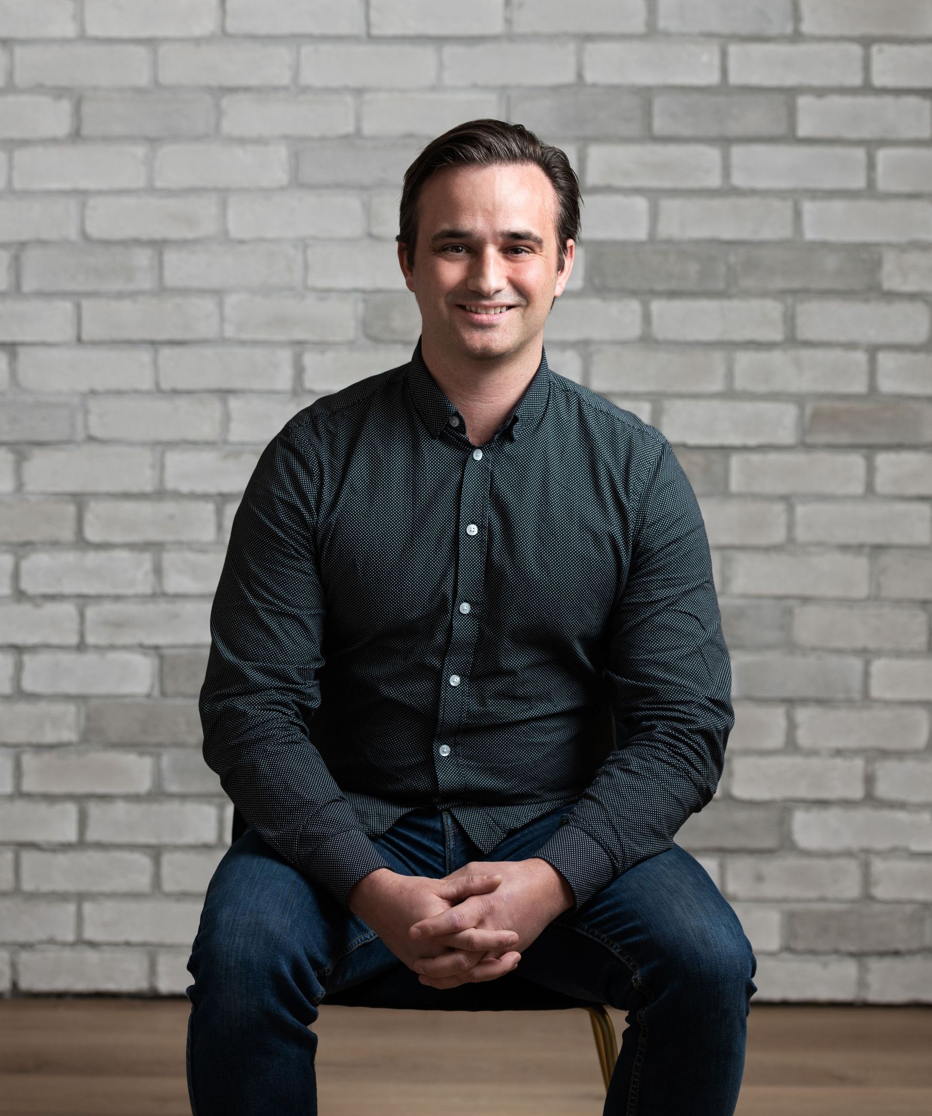a man is sitting on a chair in front of a brick wall .