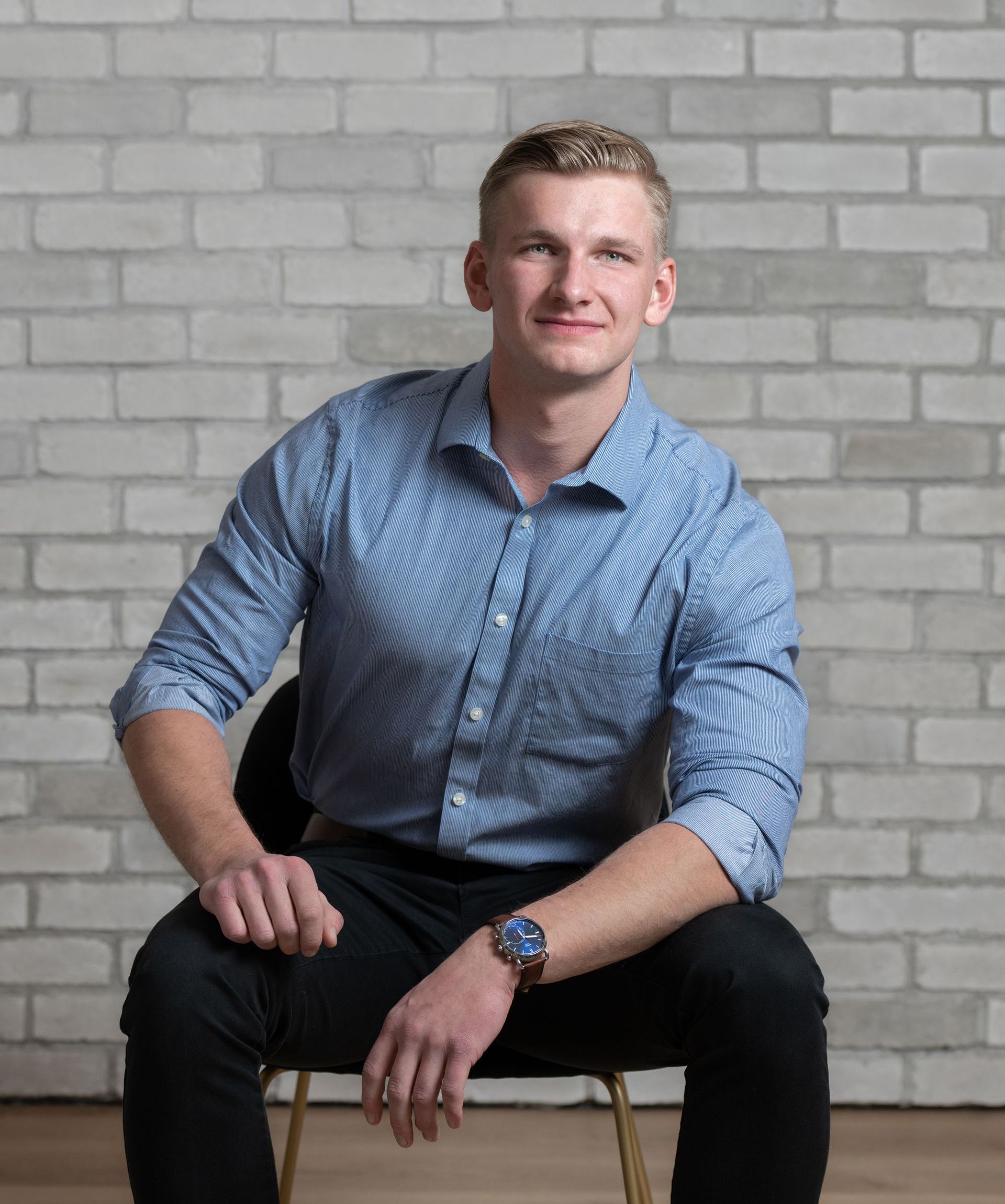 a man is sitting in a chair in front of a brick wall .
