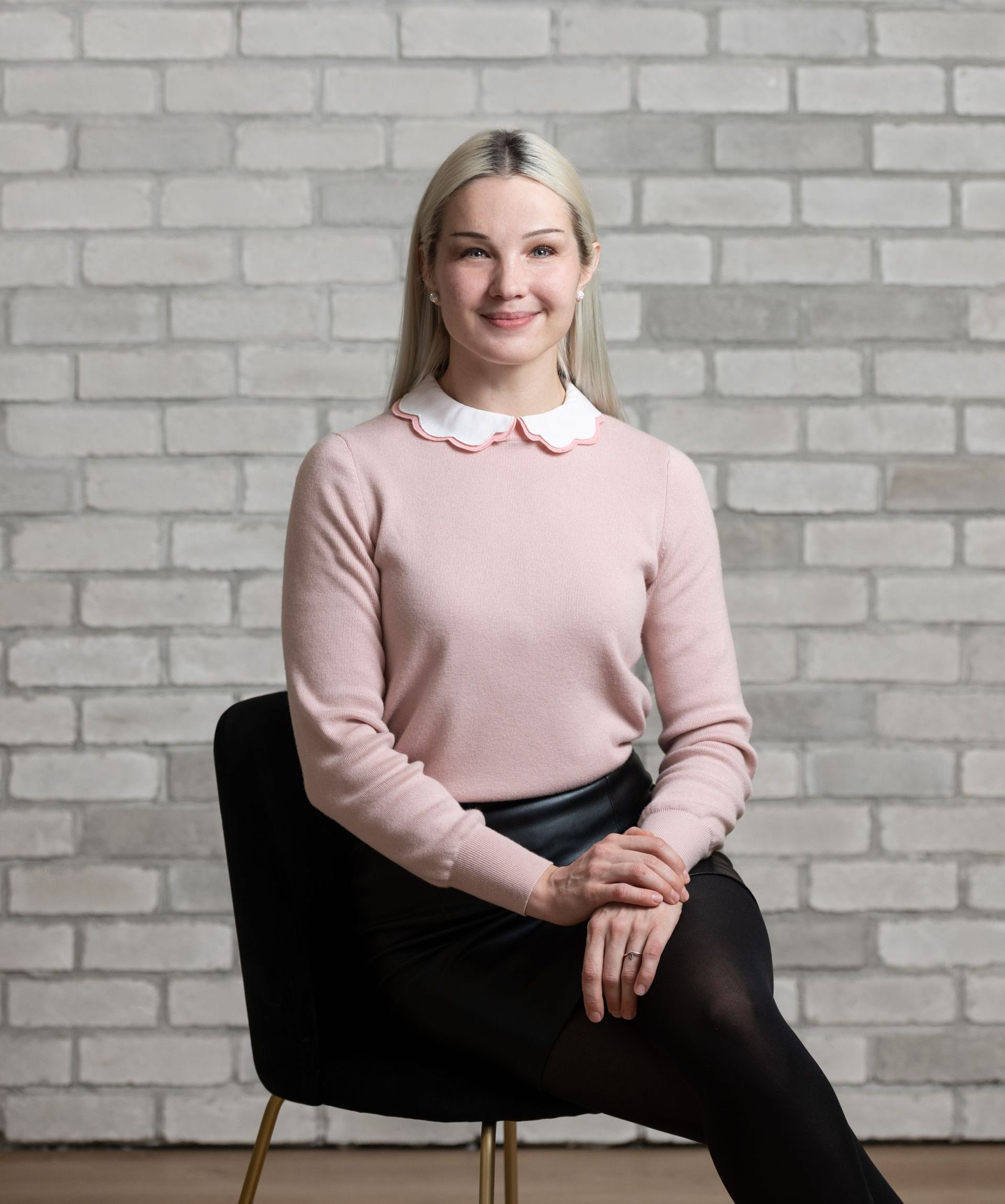 a woman is sitting in a chair in front of a brick wall .