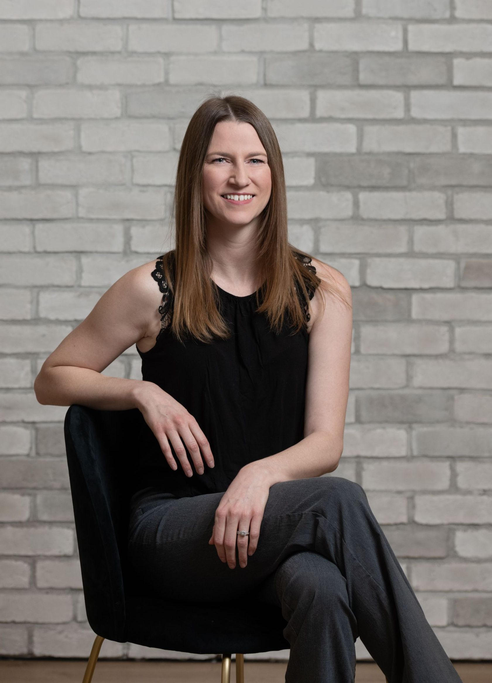 a woman is sitting in a chair in front of a brick wall .