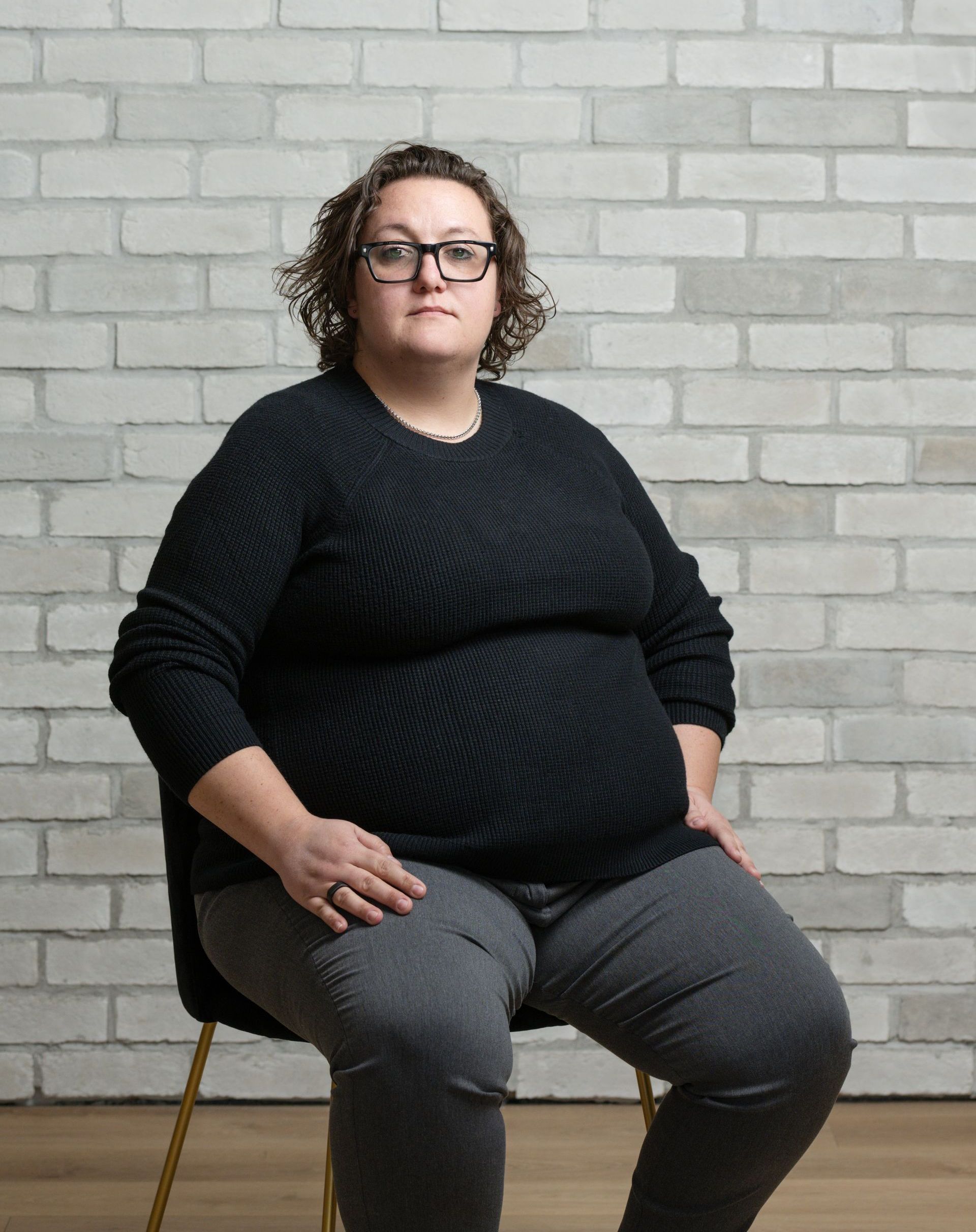 a woman is sitting in a chair in front of a brick wall .