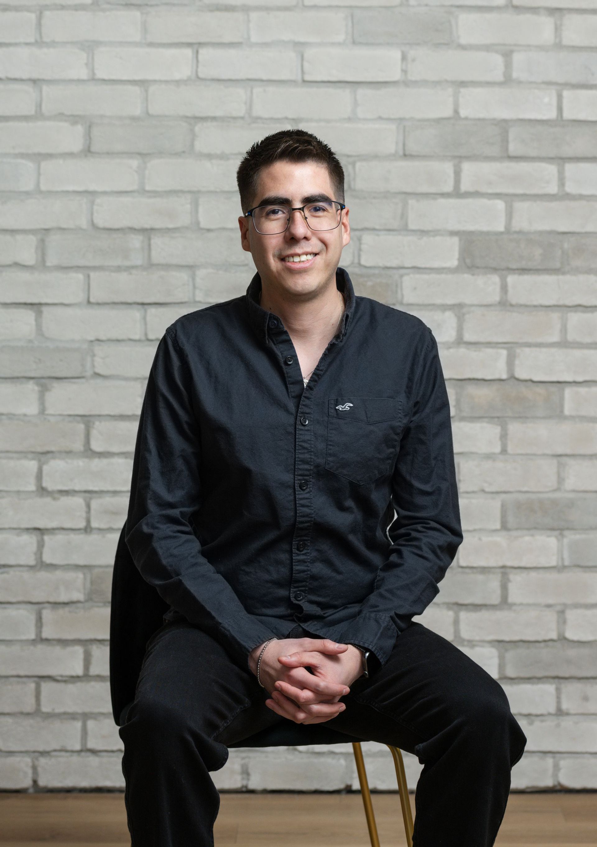 a man is sitting in a chair in front of a brick wall .