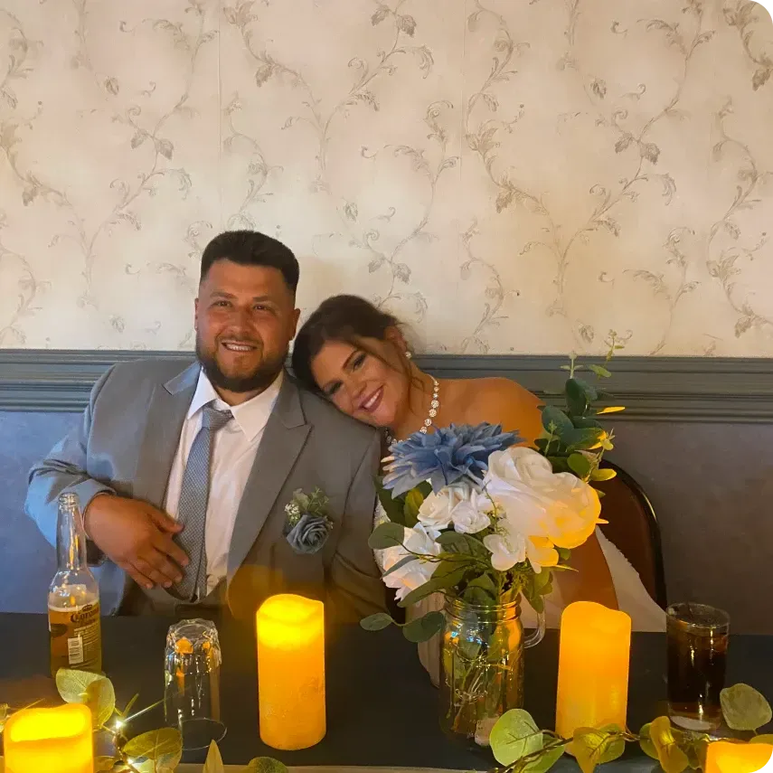 A bride and groom are posing for a picture at their wedding reception.