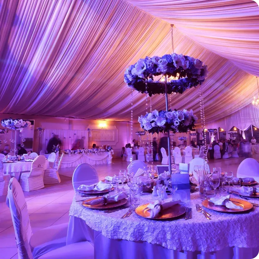 A large room with tables and chairs set up for a wedding reception