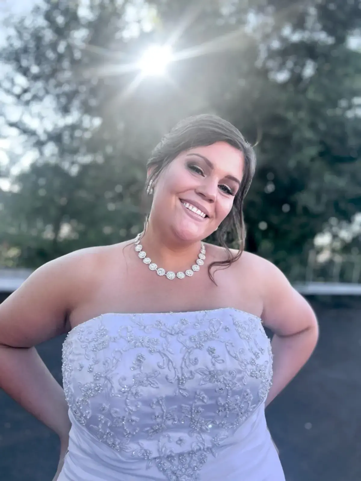 A woman in a white wedding dress is smiling for the camera.