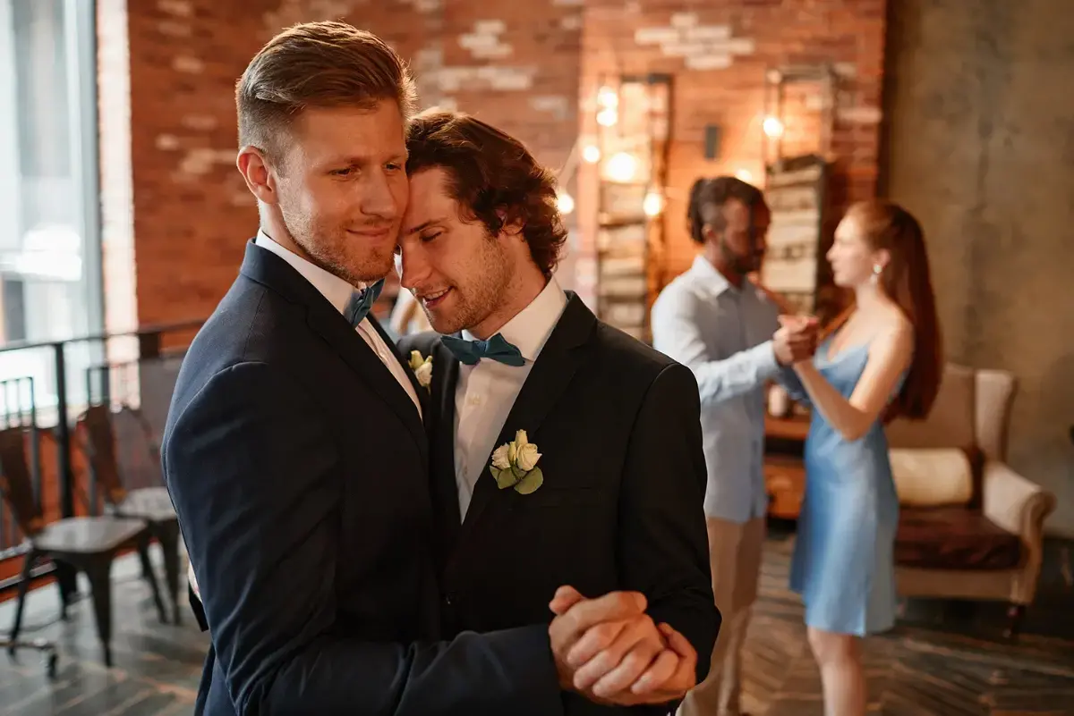 grooms are dancing together at a wedding reception.