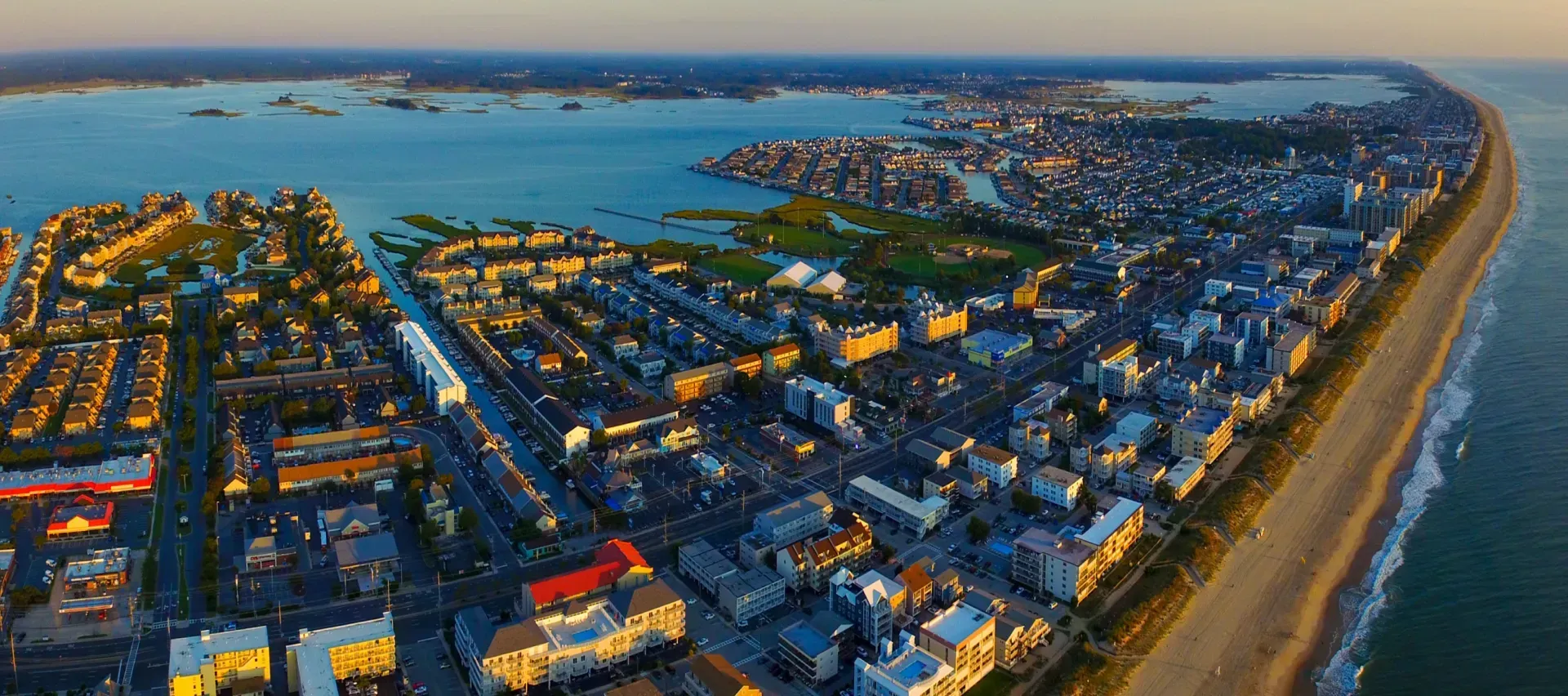 An aerial view of a city next to the ocean at sunset.