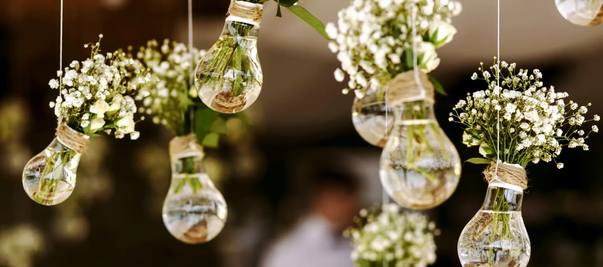 A bunch of light bulbs filled with flowers hanging from the ceiling.