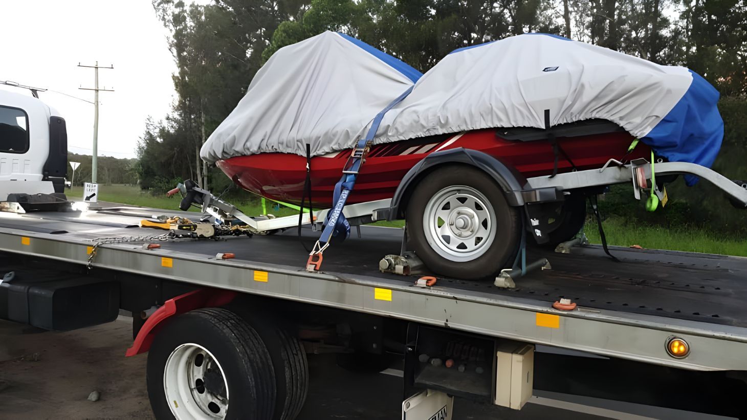 A Red Boat Is Sitting On Top Of A Tow Truck — NCM Towing Newcastle In Broadmeadow, NSW