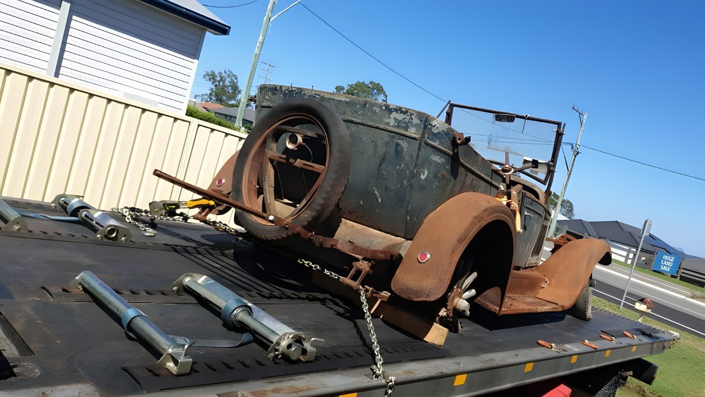 An Old Car Is Sitting On Top Of A Tow Truck — NCM Towing Newcastle In Broadmeadow, NSW
