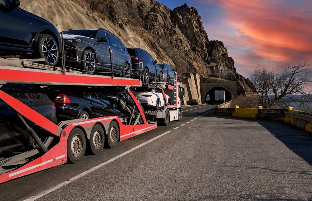 Car Carrier Truck Transporting Vehicles on a Mountain Road Near a Tunnel at Sunset — NCM Towing Newcastle In Broadmeadow, NSW