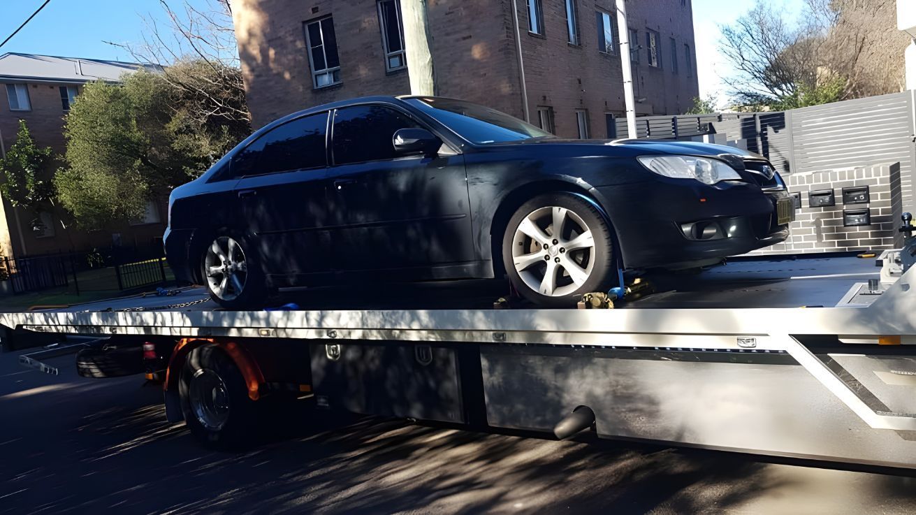 A Black Car Is Sitting On Top Of A Tow Truck — NCM Towing Newcastle In Newcastle, NSW