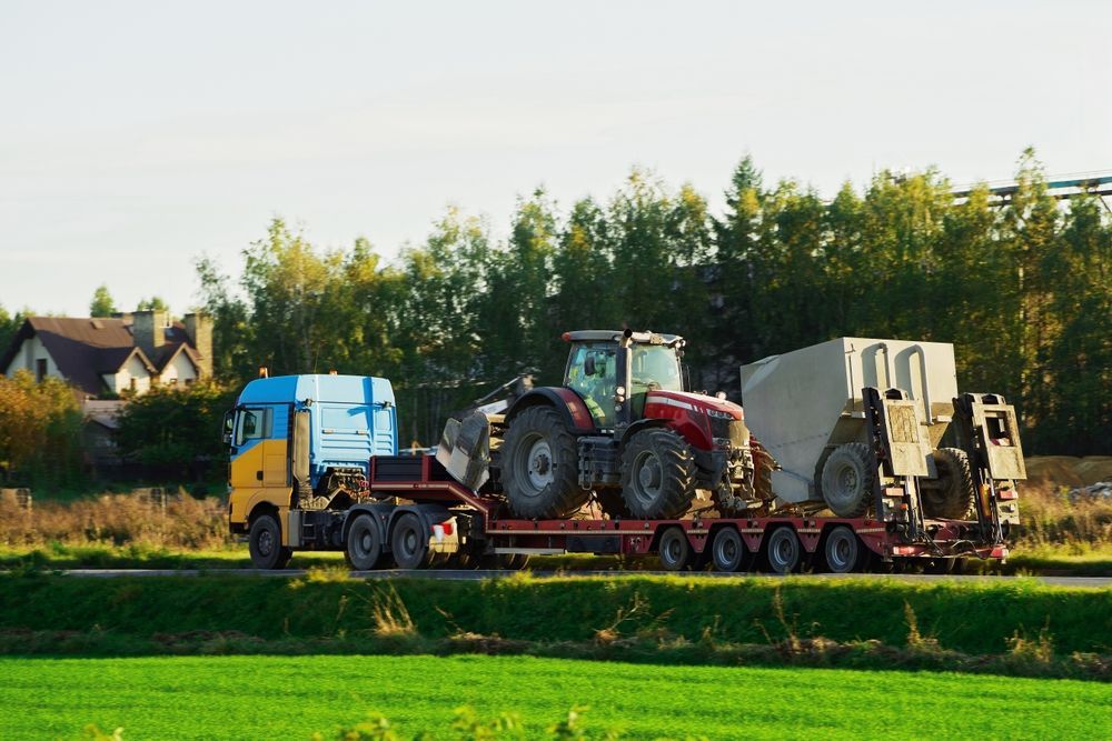 Truck Hauling a Red Tractor and Large Machinery on a Trailer — NCM Towing Newcastle In Maitland, NSW
