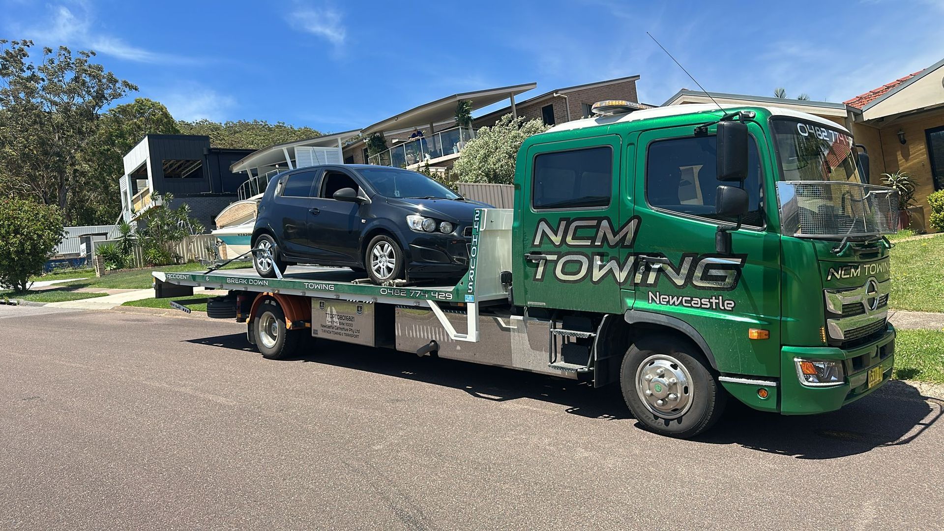 A Black Car Is Sitting On Top Of A Tow Truck — NCM Towing Newcastle In Broadmeadow, NSW