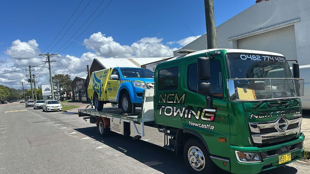 A Yellow And Blue Van Being Towed On Bed Of A Tow Truck — NCM Towing Newcastle In Broadmeadow, NSW